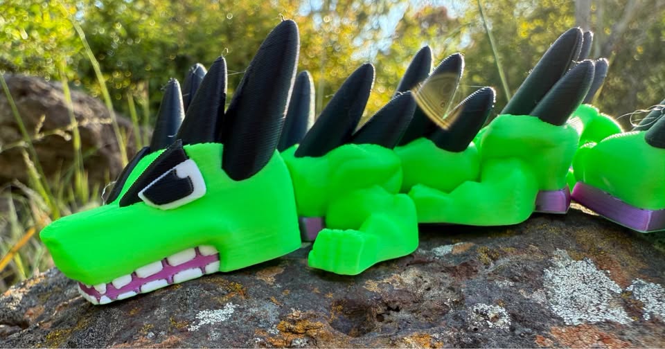 Green dragon 3d printed with black horns on a rocky surface