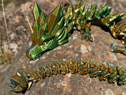 Green metallic dragon sculpture on a rocky surface