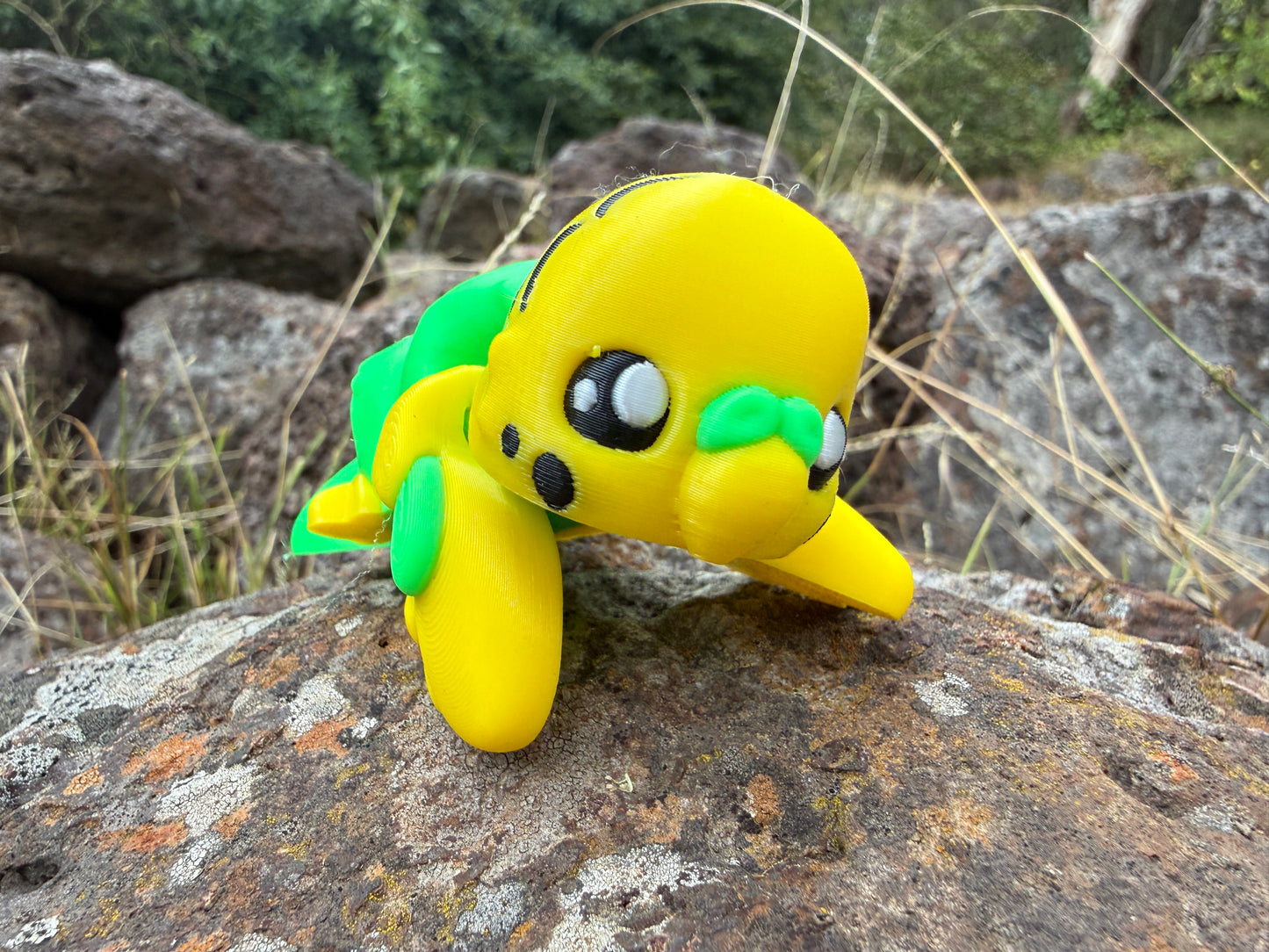 Yellow 3d printed budgie with green bits on a rock