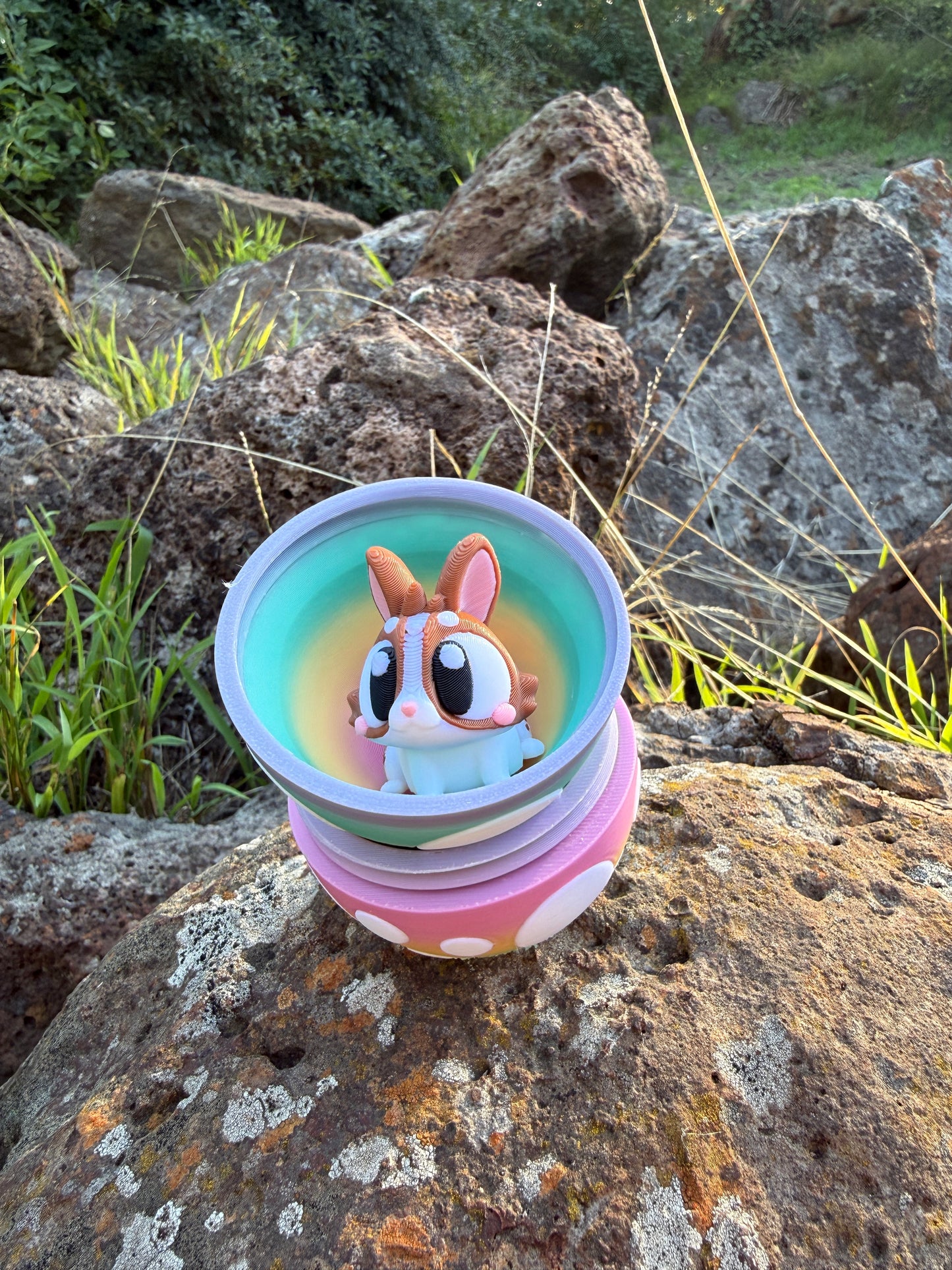 Colorful 3d printed egg halves on top of each other with cartoon like 3d printed bunny design on a rocky surface