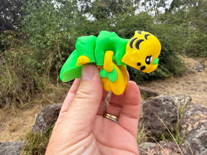 3d printed budgie yellow and green held by a hand with a natural background