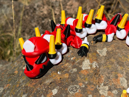 firefighter dragon 3d printer with red, white, and yellow segments on a rocky surface 