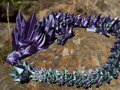 Purple and green dragon-like creature on a textured surface