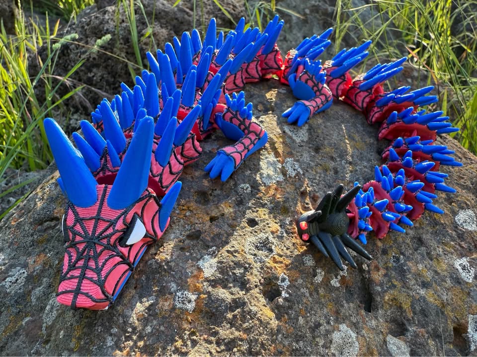 3d printed spider dragon web covered with blue and red spikes on a stone surface