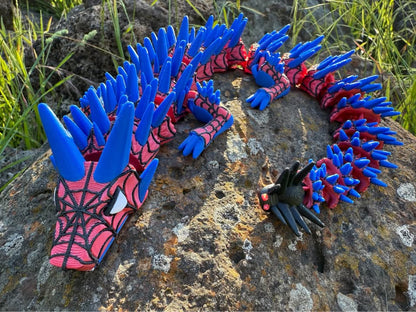 3d printed spider dragon web covered with blue and red spikes on a stone surface
