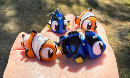 Four small fish-shaped 3d printed held in a hand with a blurred natural background
