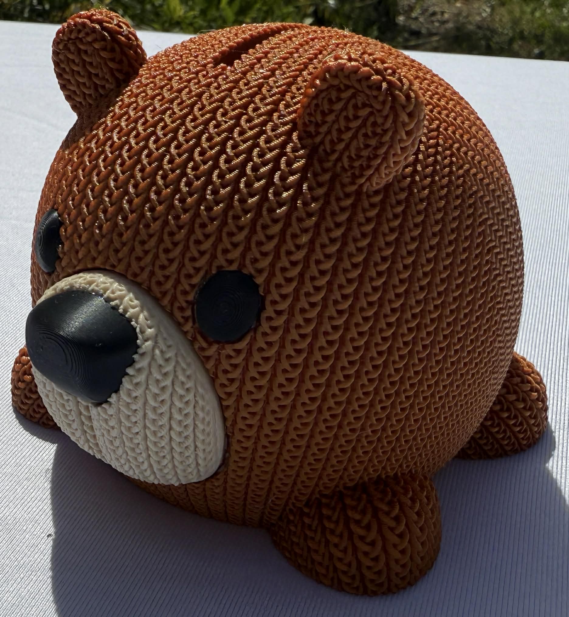 Knitted bear-shaped piggy bank on a white surface