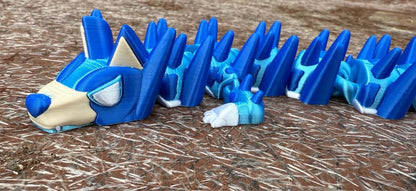 Blue and beige3d printed dog dragon with spikes on a wooden surface