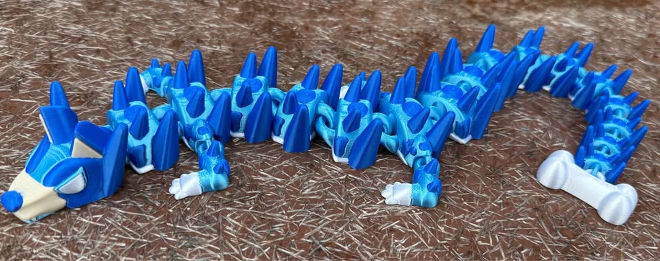 Blue and white 3d printed dog dragon on a brown surface