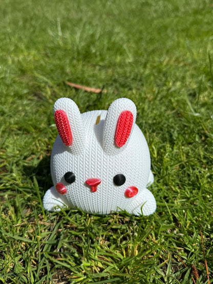3D printed White knitted bunny moneybox with pink accents on a grassy background