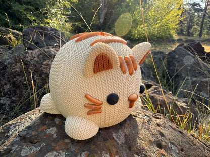beige and copper Knitted cat money box 3d printed on a rock with a natural background