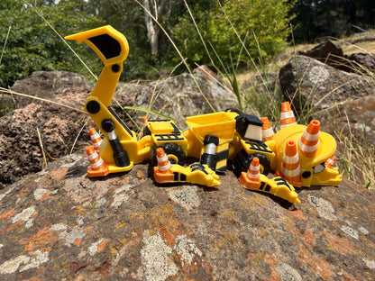 3D printed excavator mini dragon with traffic cones on a rocky surface. tail up showing usable bucket