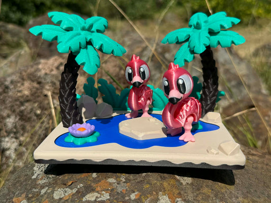 Two pink flamingoes 3d printed articulated characters on a miniature landscape with palm trees and a pond.