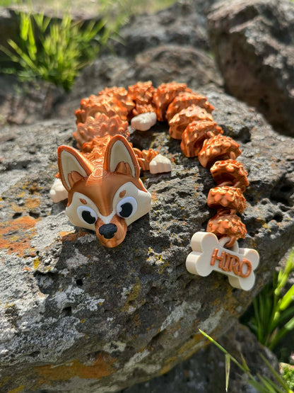 3d printed German Shepard dragon with a bone-shaped tag that had Hiro printed on it on a rocky surface