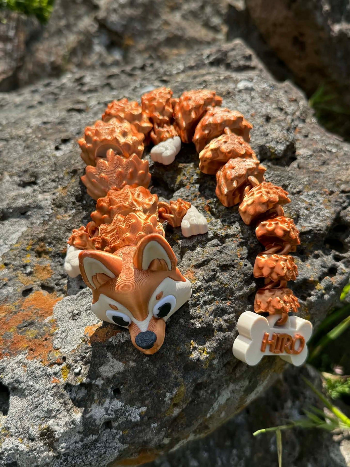 3d printed German Shepard dragon with bone shaped tail on a rocky surface