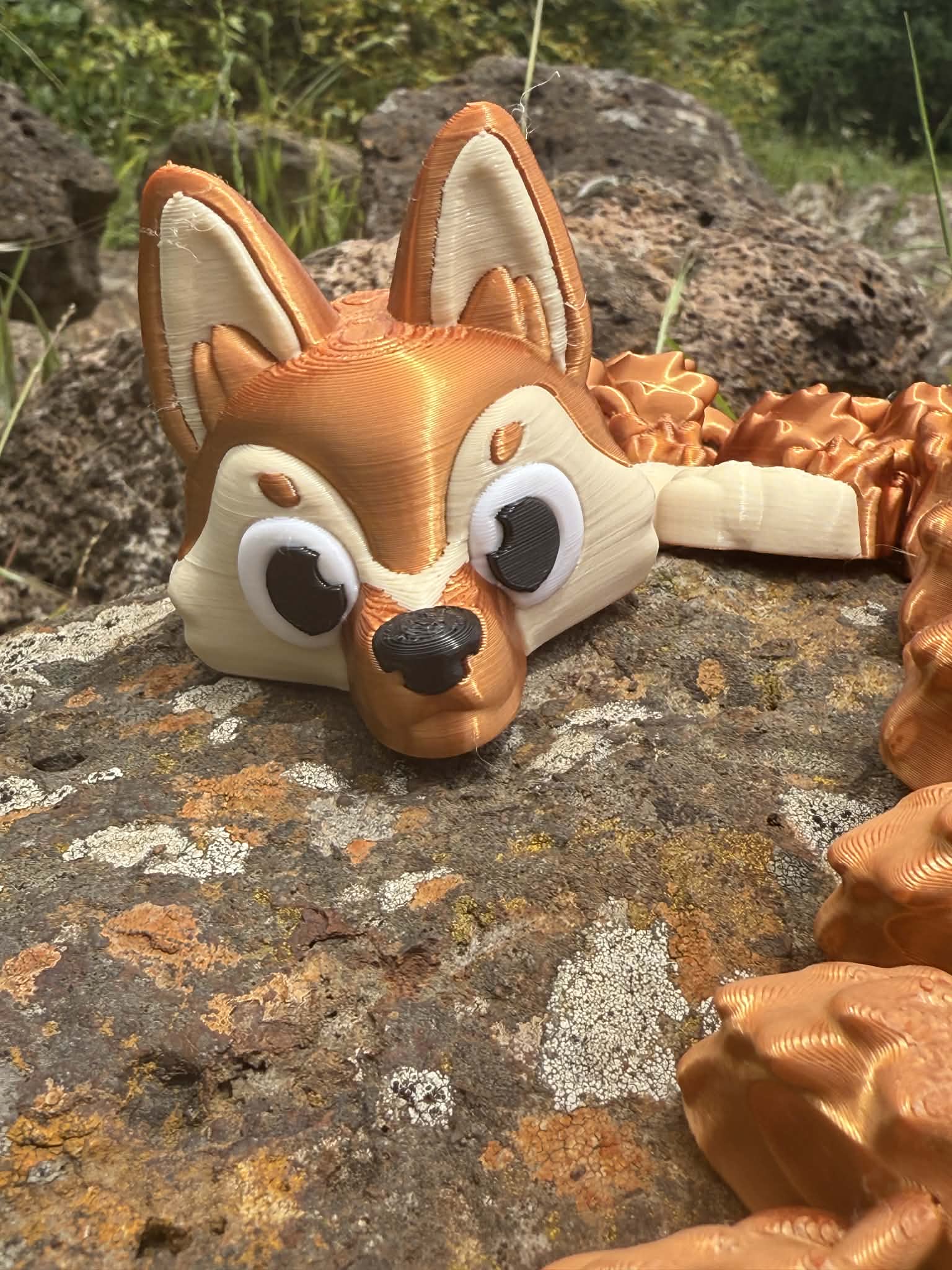 3d printed close up of head of German Shepard dragon on rocky surface with greenery in the background
