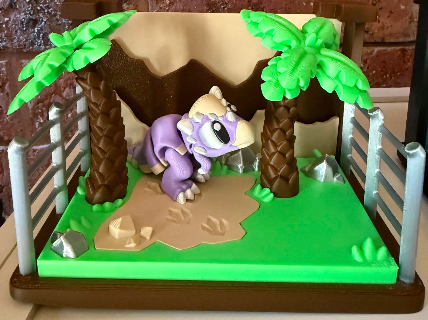 3d printed purple dino in a desert-like setting with palm trees and rocks.
