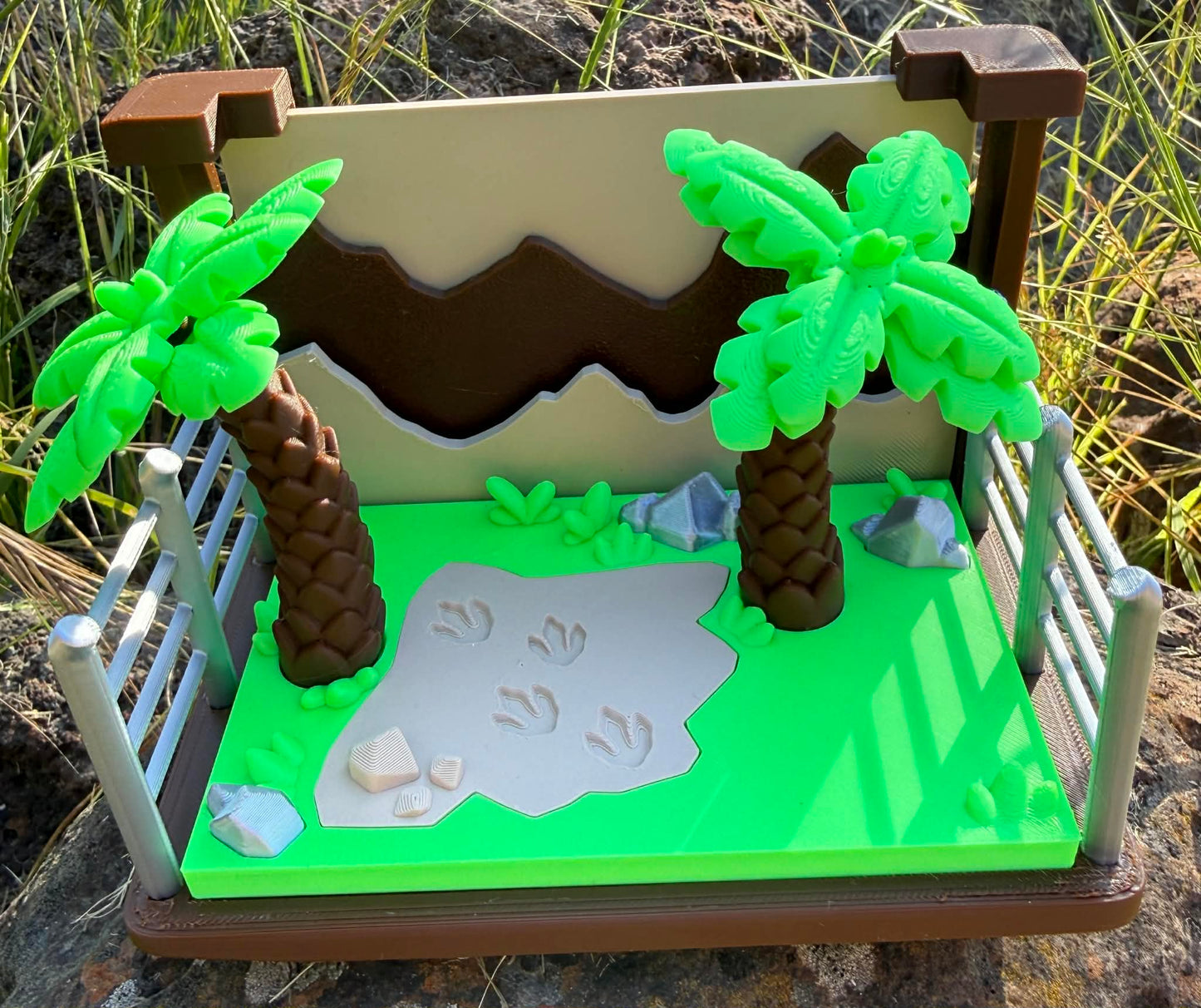 3d printed y set with a dino scene including palm trees, sand, and rocks.