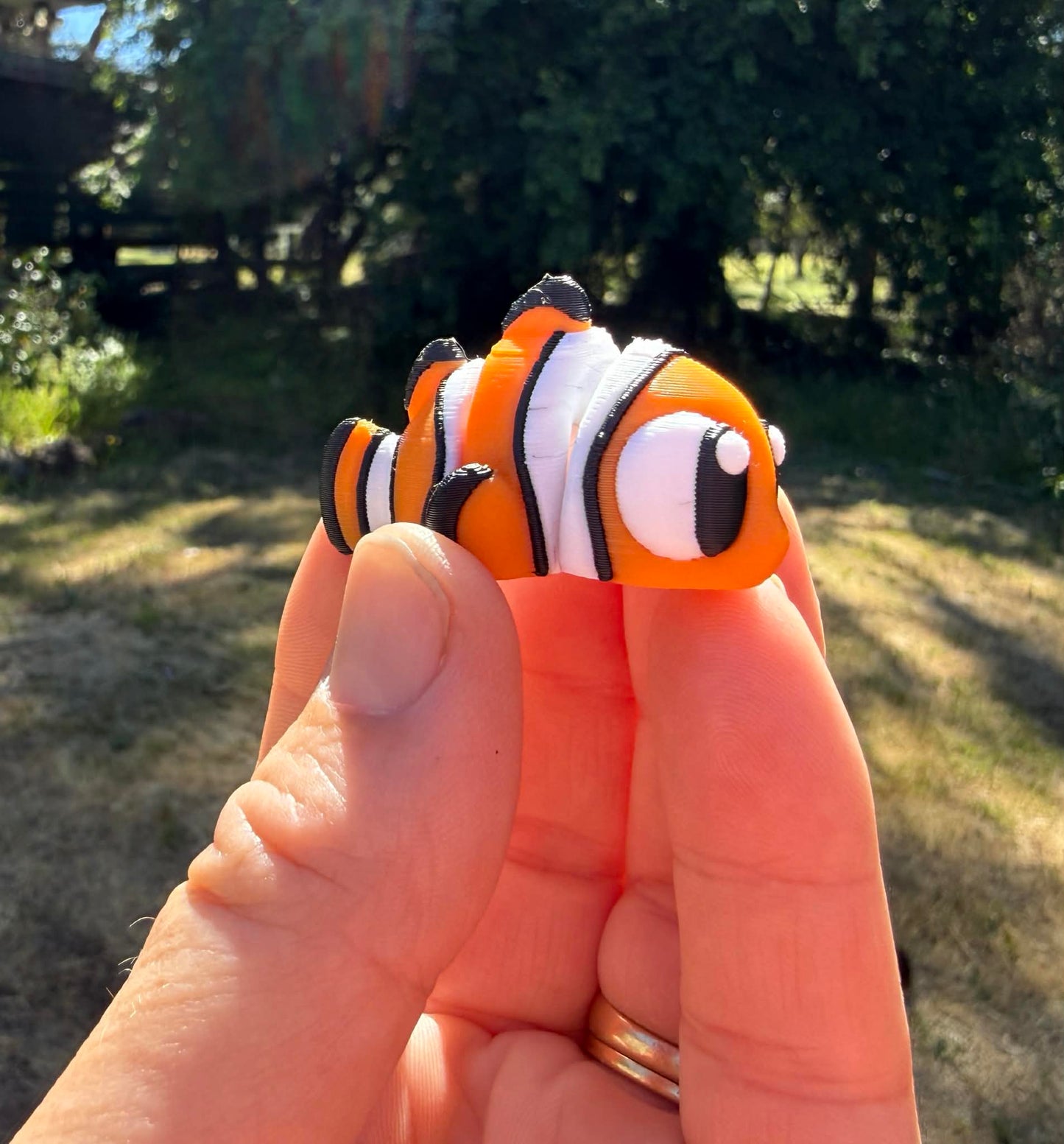 Hand with 3D printed clownfish against a natural background