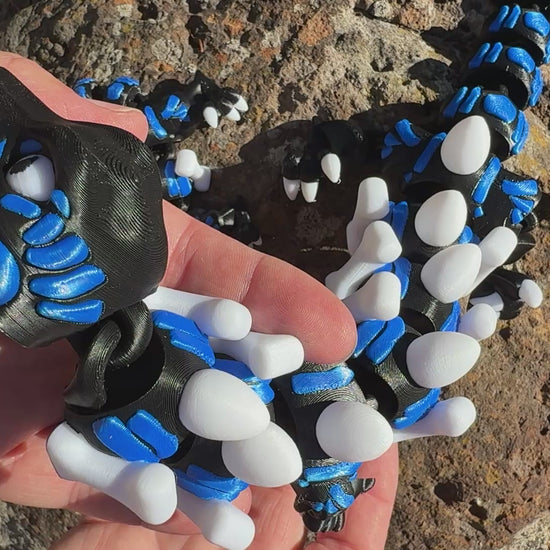 3D printed raptor black and blue. large and small with steak detail tail. bone and egg details down their back. shacking 