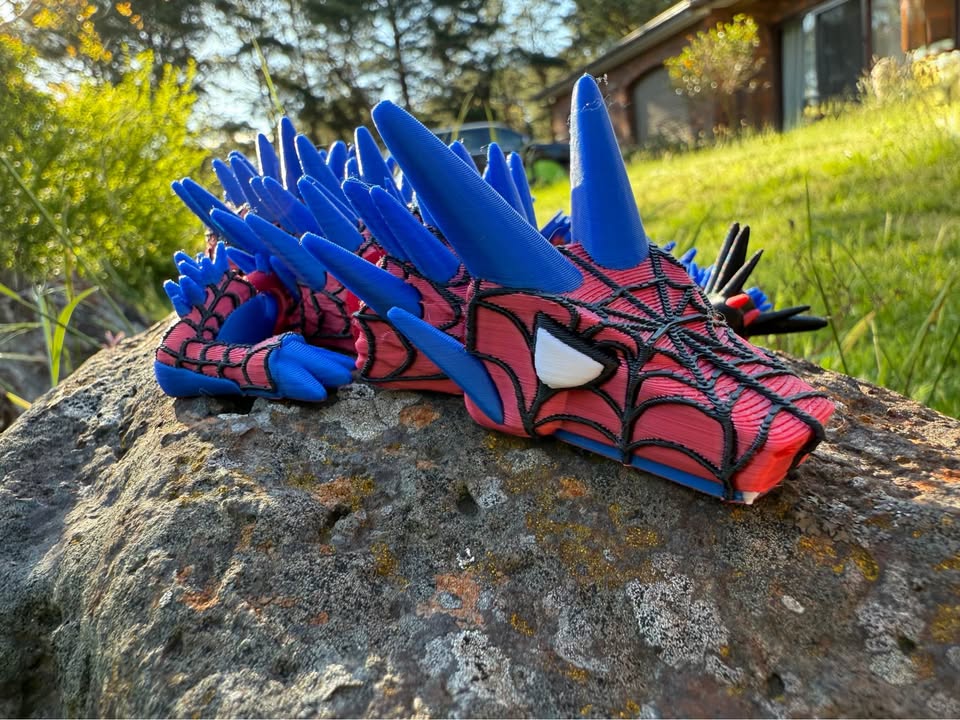 3d printed dragon with Spider-Man design on a rock outdoors