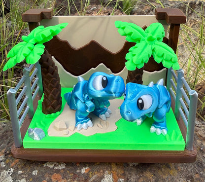 3D printed dinosaurs in a miniature landscape with trees and a fence.