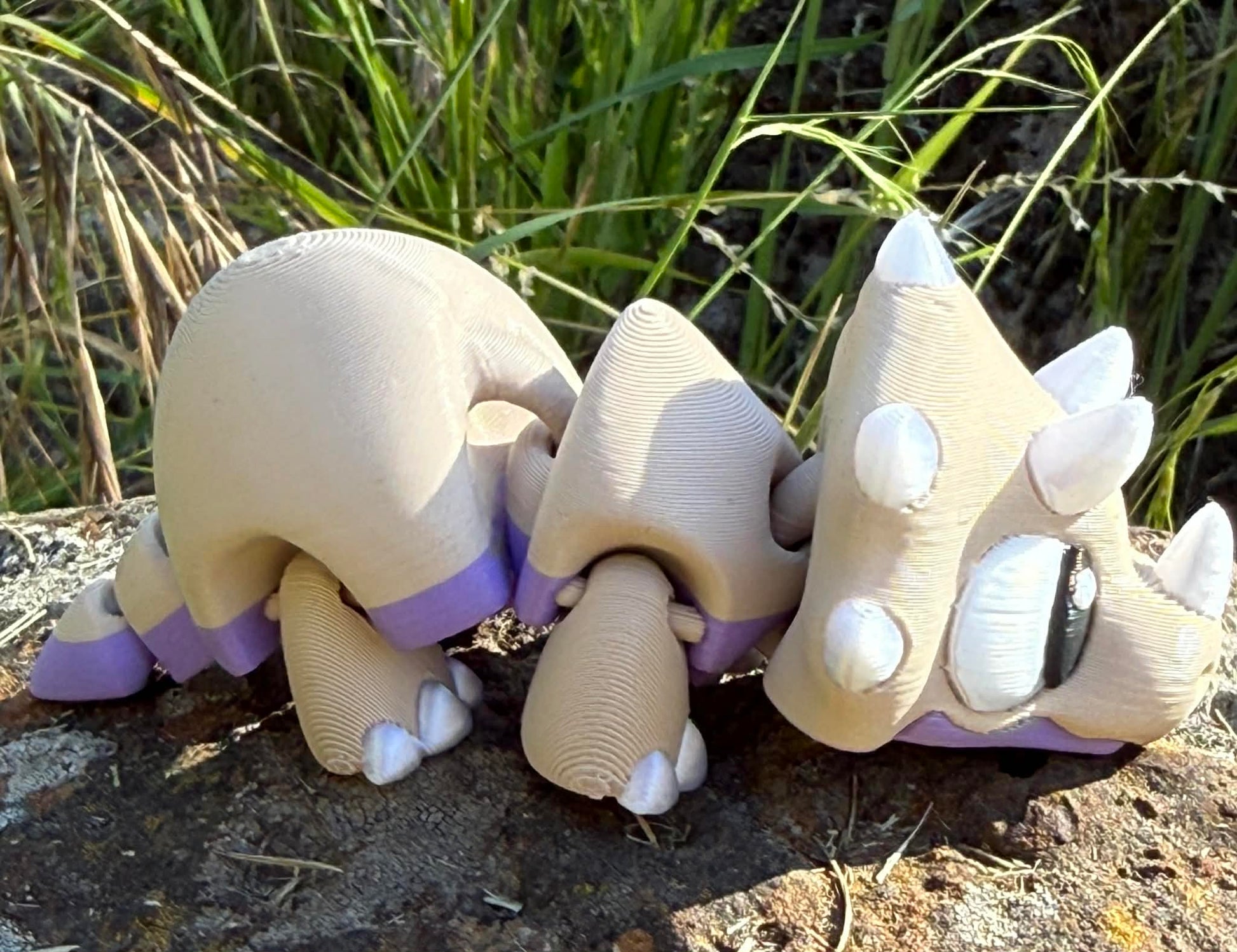 3d printed  triceratops on a stone surface with grass in the background