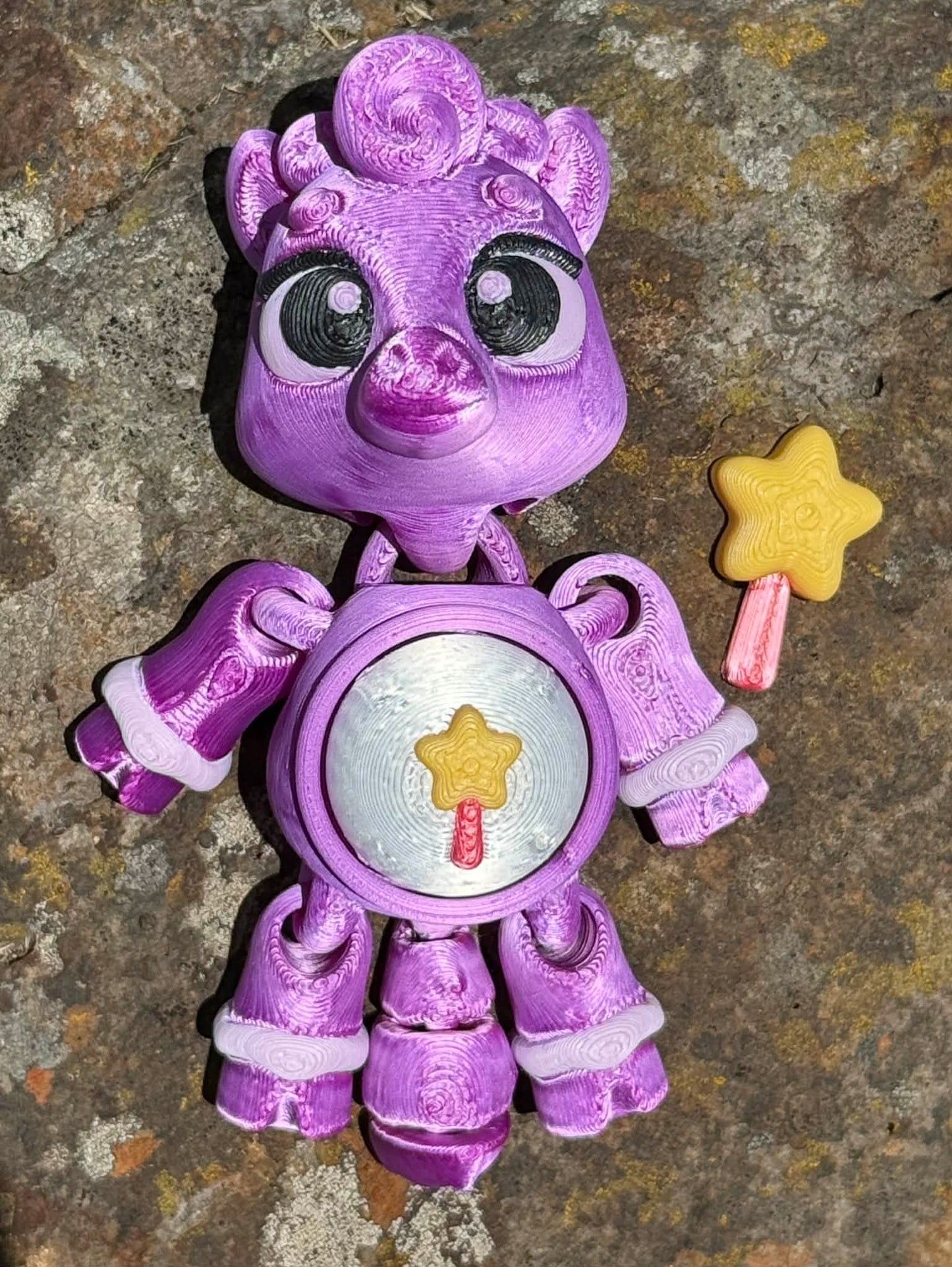 Purple 3D printed pony with star wand design on the tummy on a textured surface 
