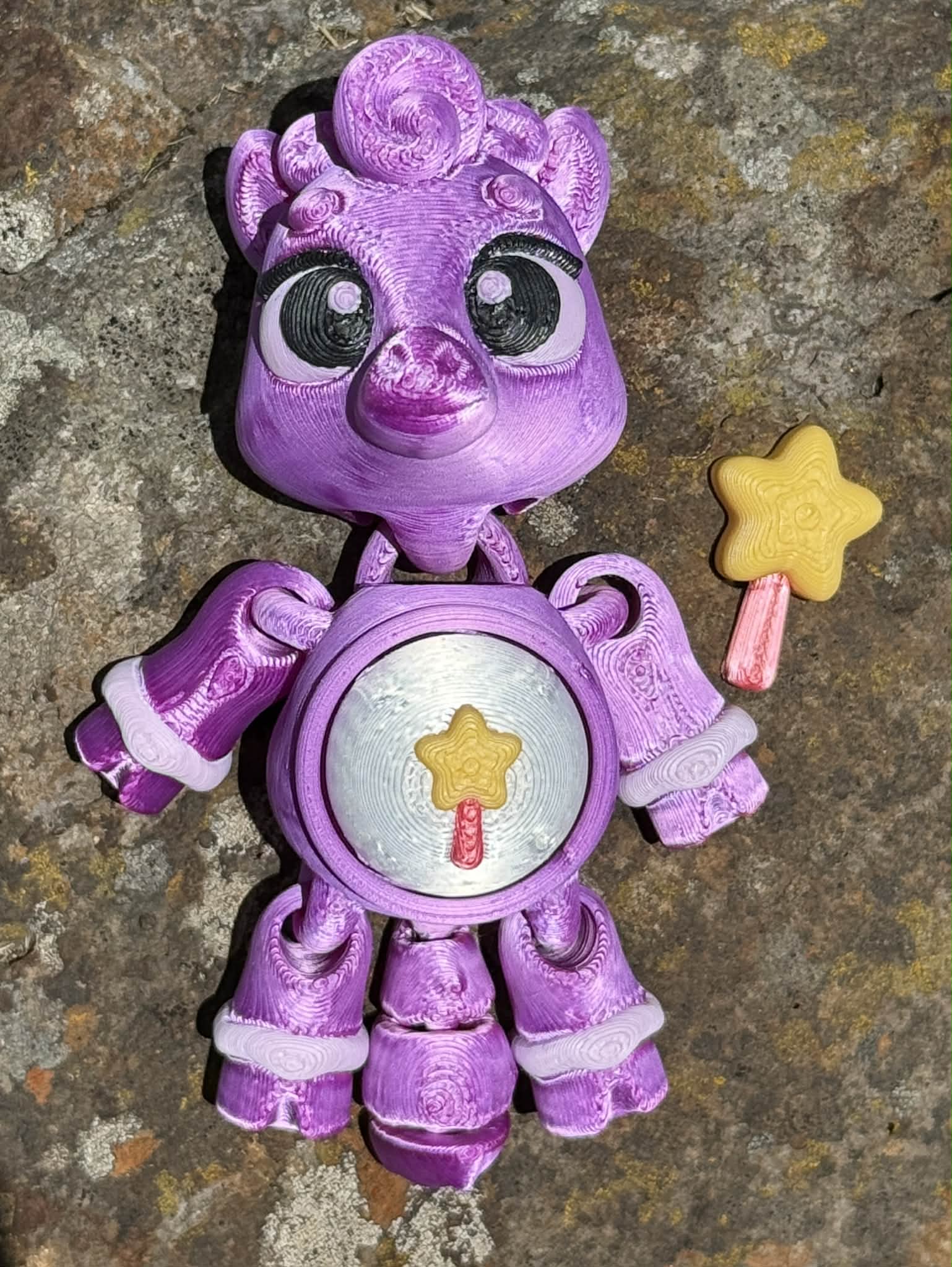 Purple 3D printed pony with star wand design on the tummy on a textured surface 