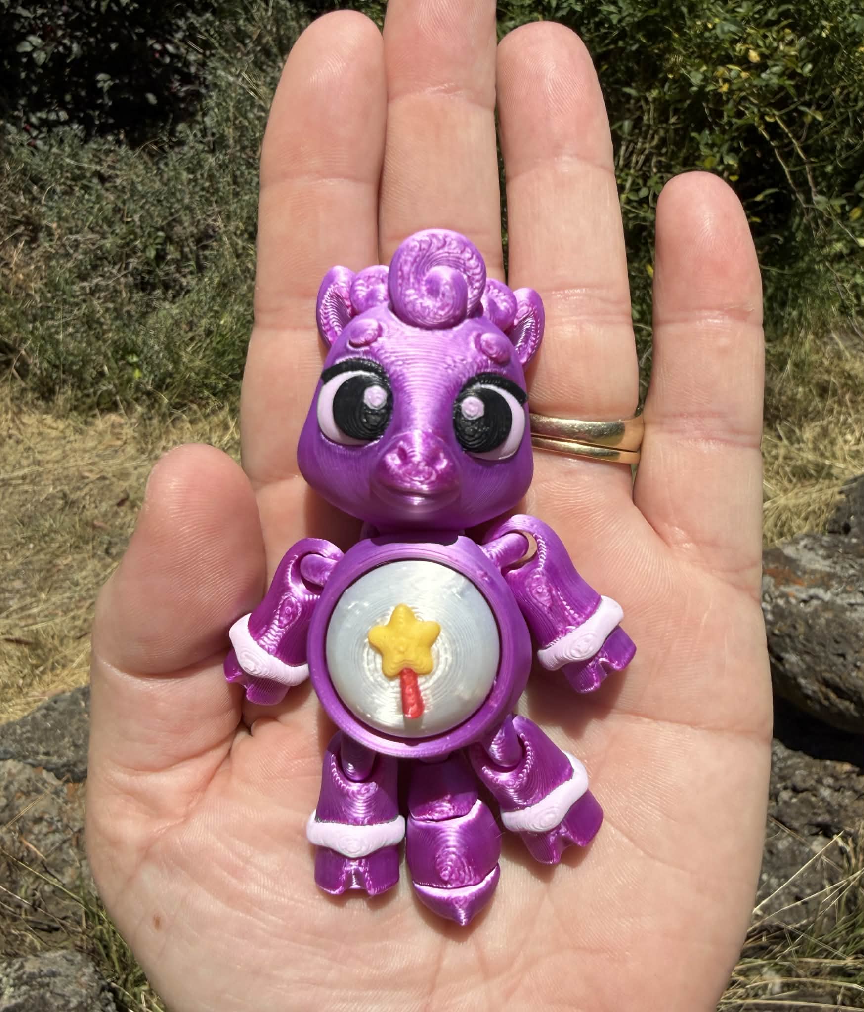 Purple 3D printed  horse  held in a hand with a natural background