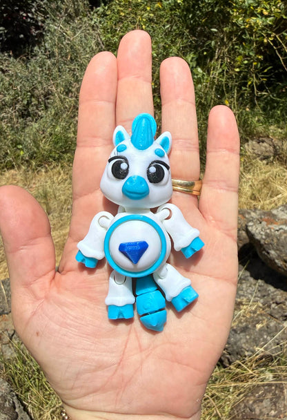 Small blue and white 3D printed pony held in a hand with a natural background