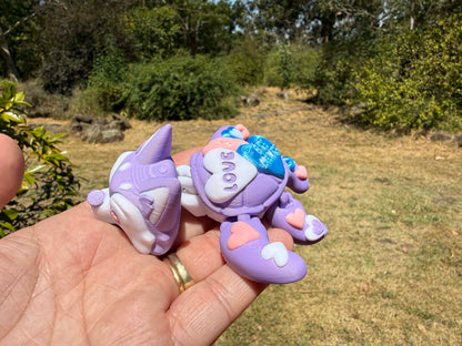 purple and blue 3d printed turtle/husky on a hand with grass in the background