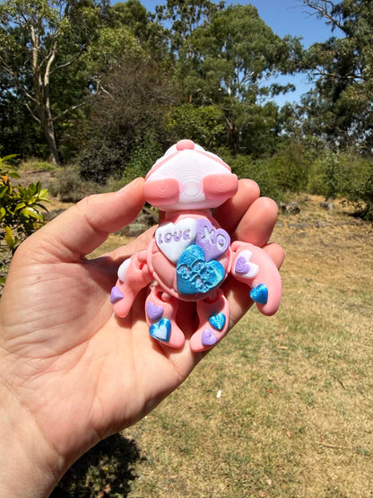 pink and blue 3d printed turtle/panda on a hand with grass in the background