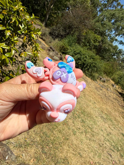pink and blue 3d printed turtle/panda on a hand with grass in the background