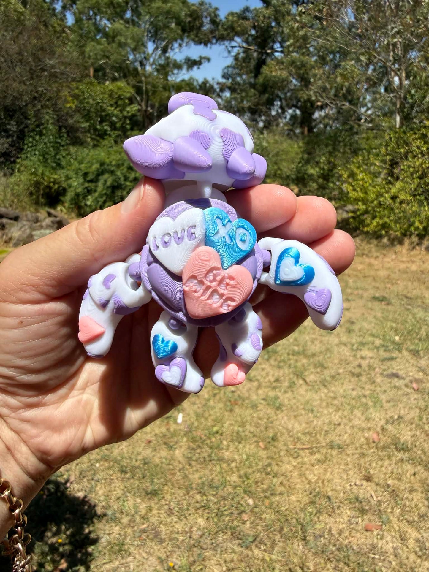 purple and blue 3d printed turtle/cow on a hand with grass in the background