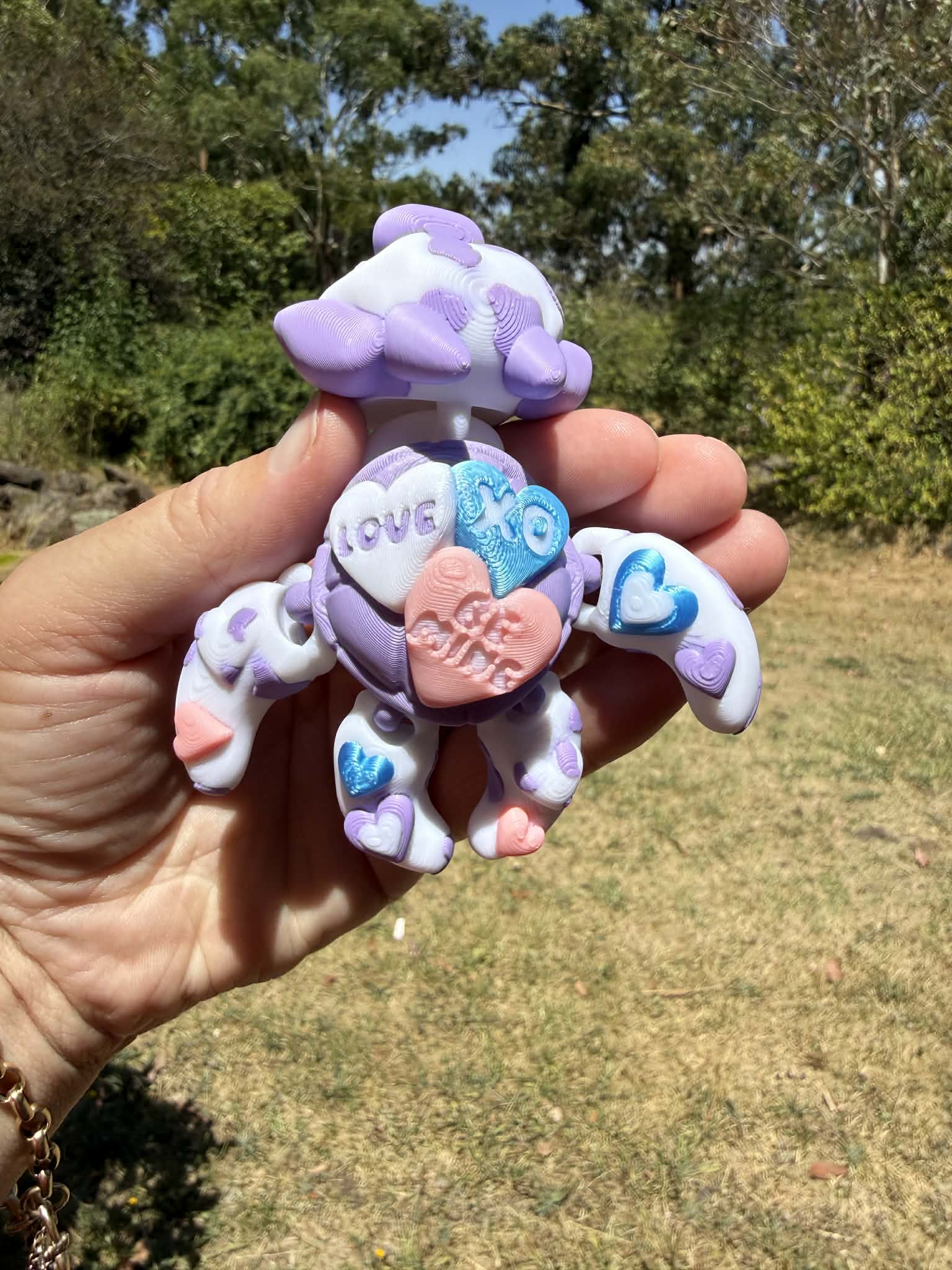 purple and blue 3d printed turtle/cow on a hand with grass in the background