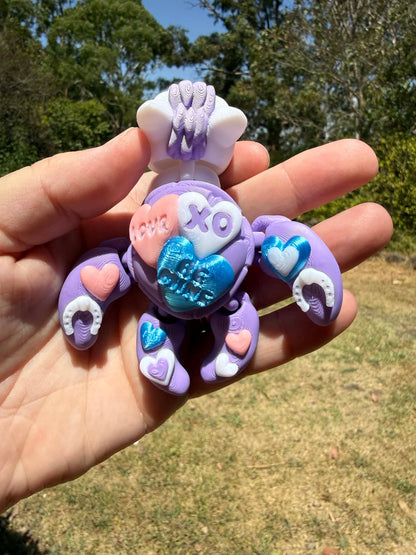 purple and blue 3d printed turtle/horse on a hand with grass in the background