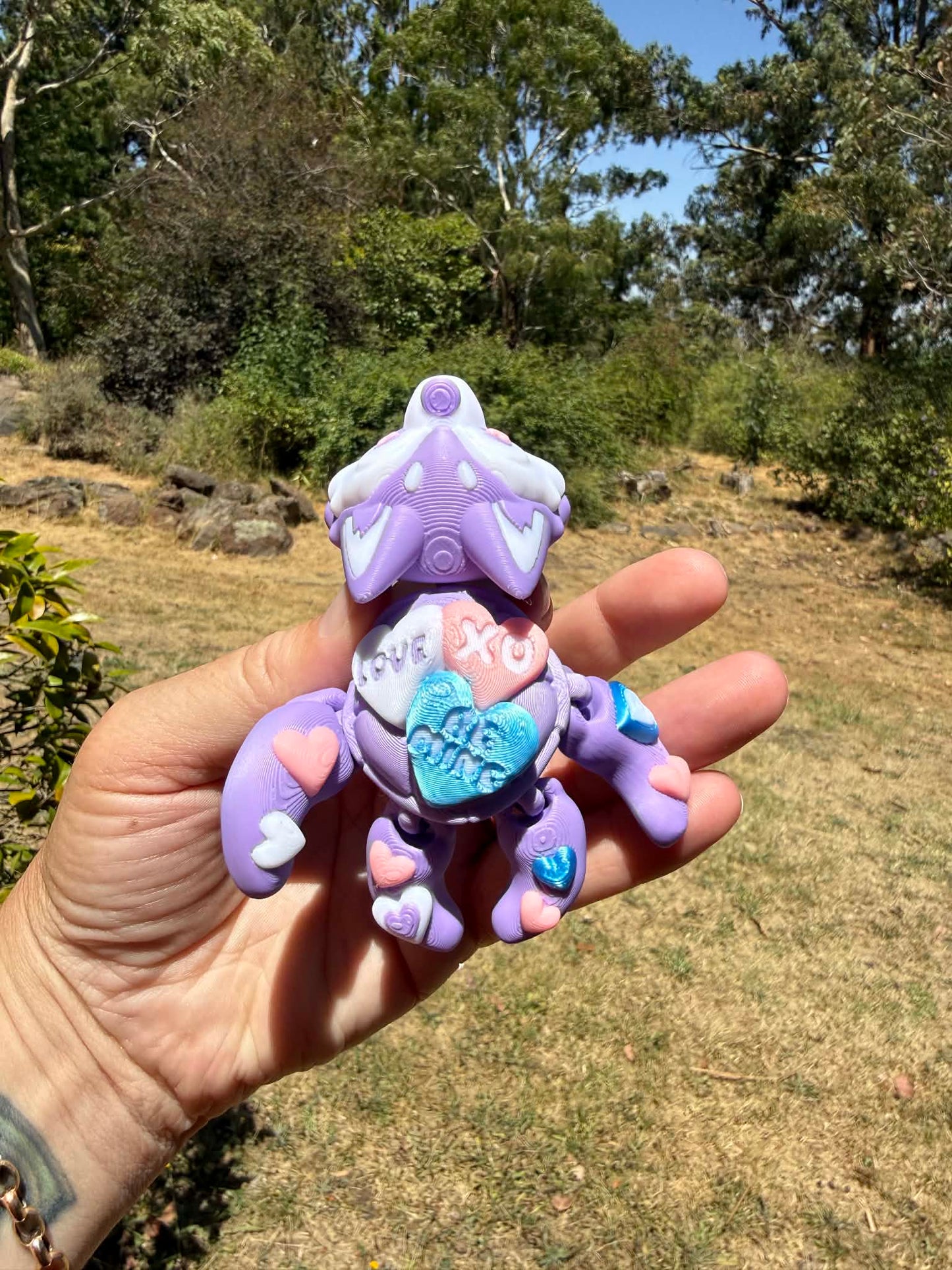 purple and blue 3d printed turtle/husky on a hand with grass in the background