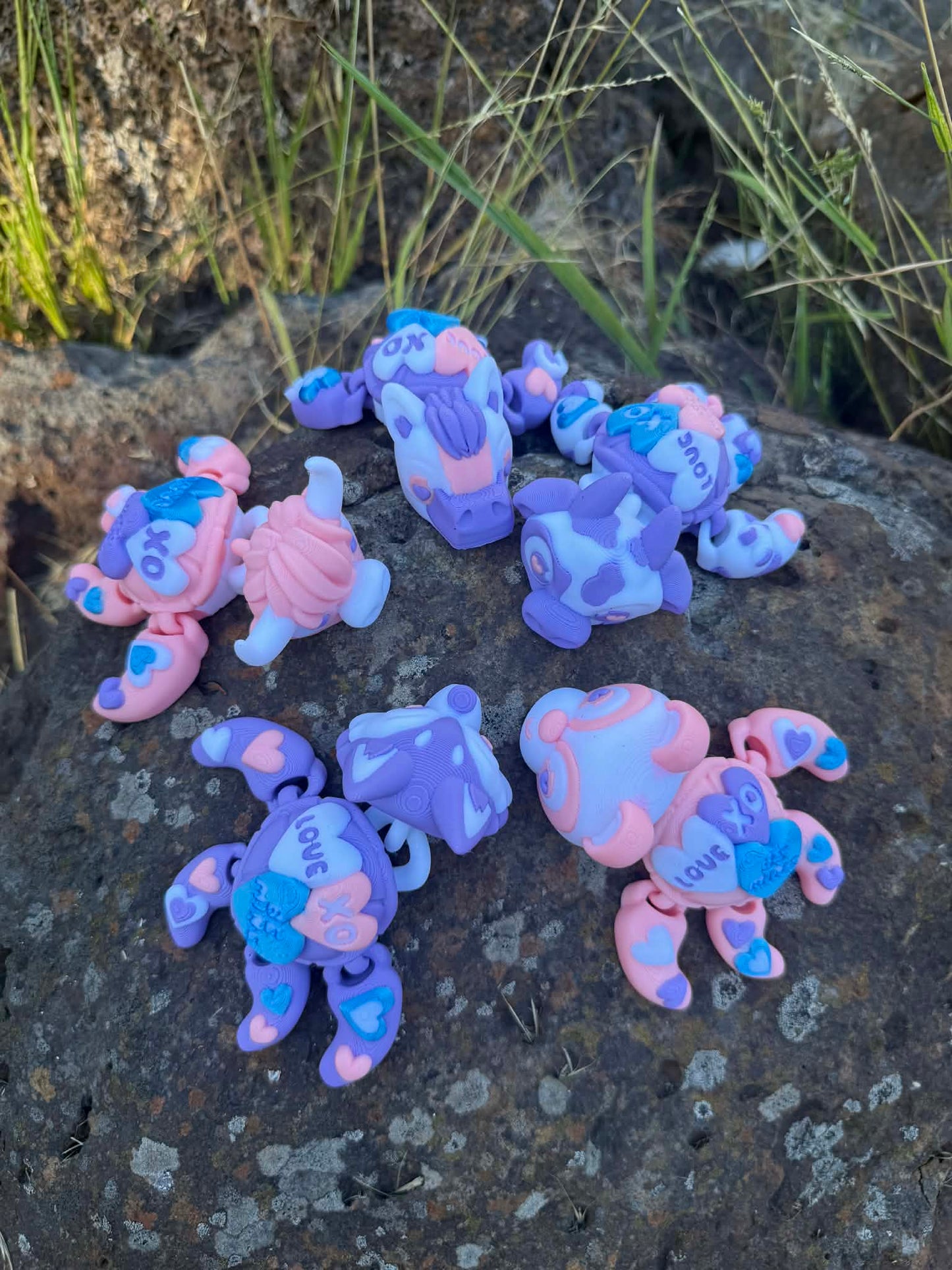 Set of colorful 3d printed turtle animal  on a stone surface with grass in the background