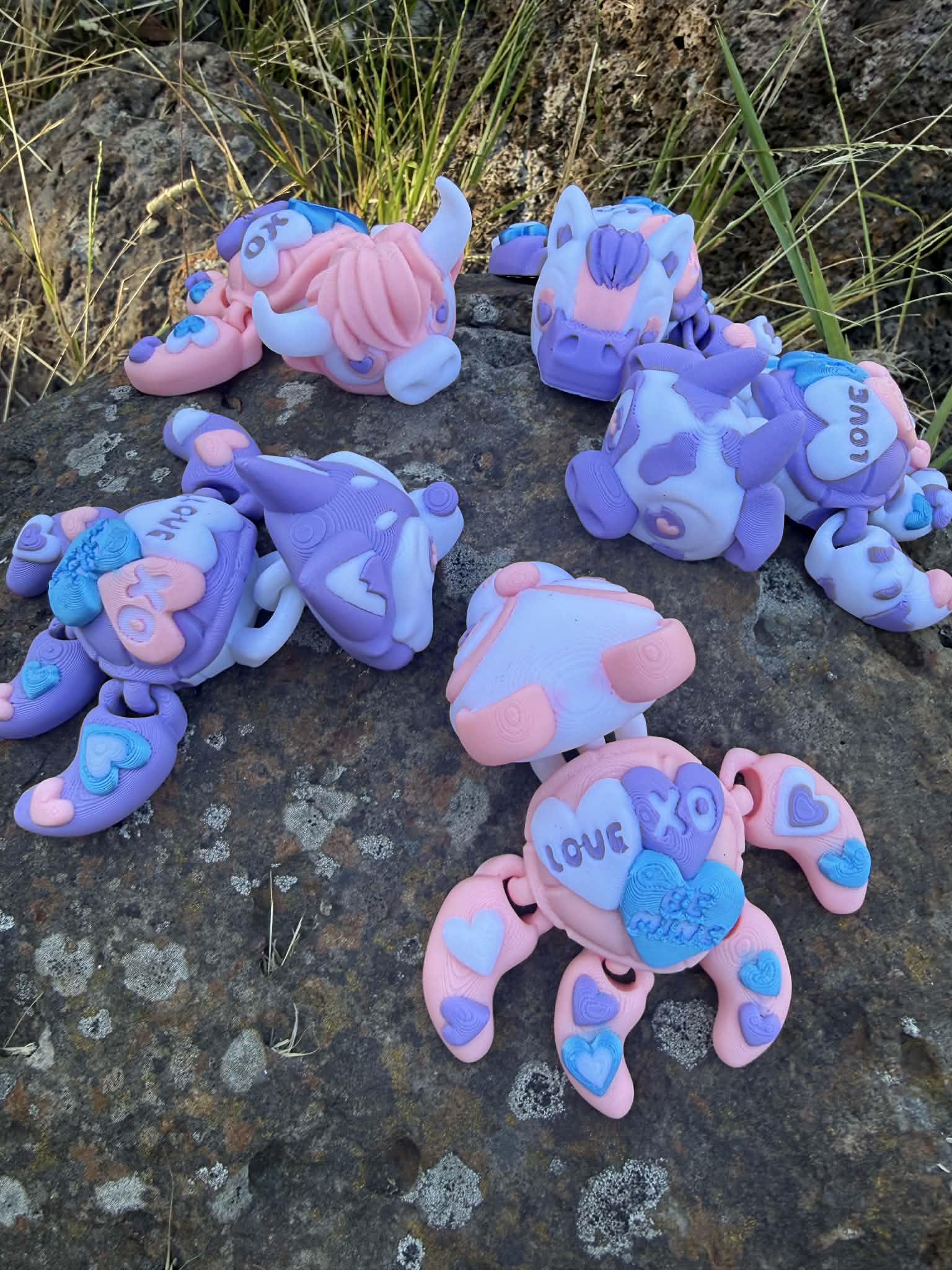 Set of colorful turtle-shaped toys on a rocky surface with grass. one panda, husky, cow, highland cow and horse