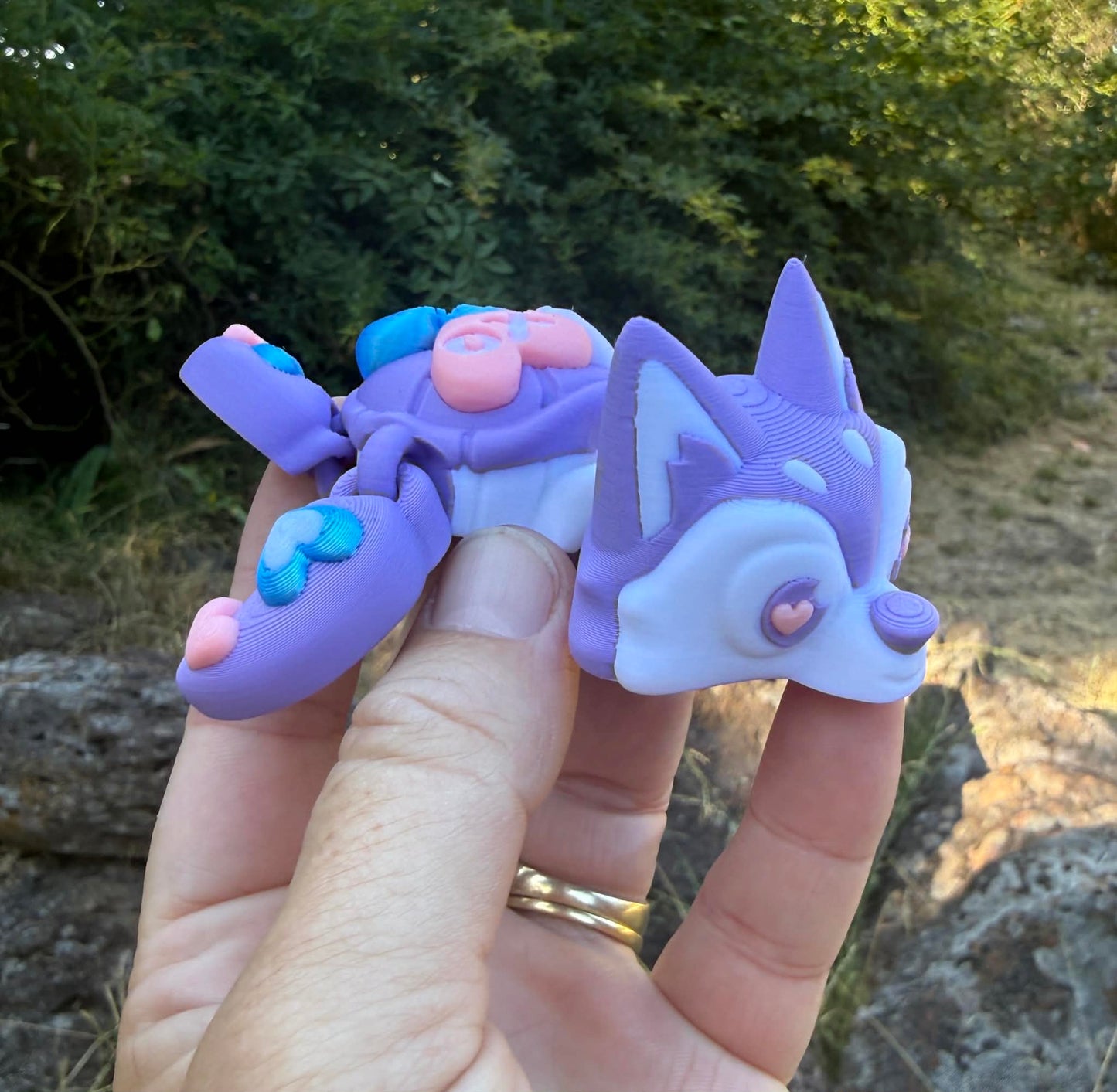 purple and blue 3d printed turtle/husky on a rock with grass in the background